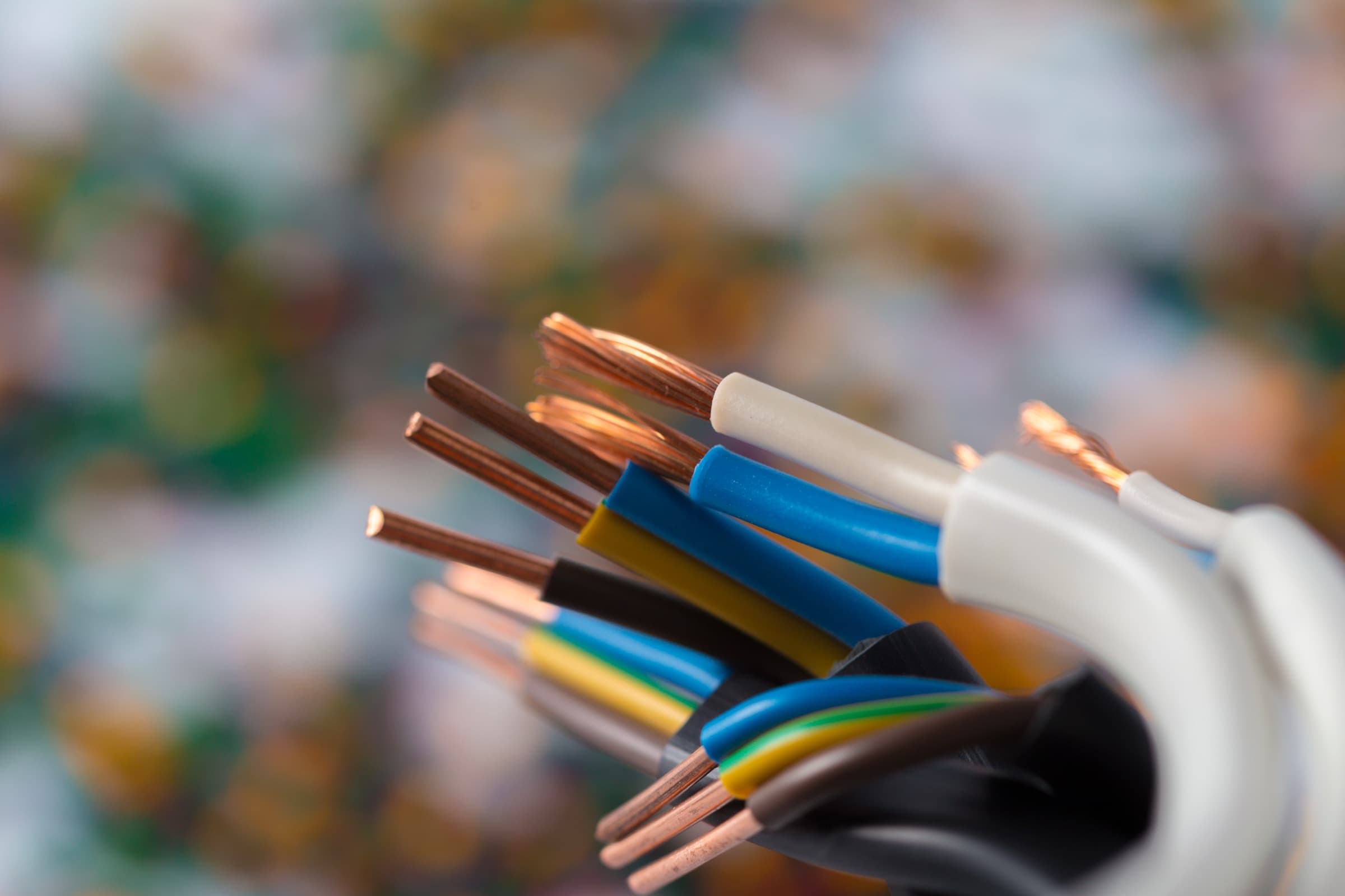 Close-up of a stripped residential cable showing copper conductors and color-coded insulation