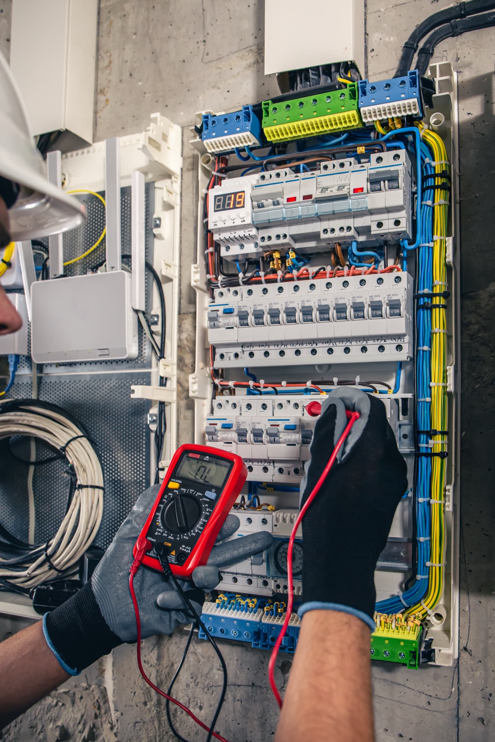 Licensed electrician testing a residential distribution panel with a multimeter